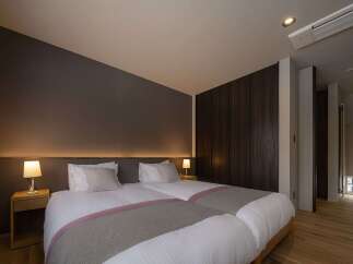 Experience comfort and style in this modern hotel room featuring two plush twin beds, perfect for a restful night's sleep.