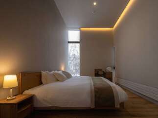 Experience serene comfort in this modern bedroom, featuring a plush king-sized bed with crisp white linens and a stylish wooden headboard.