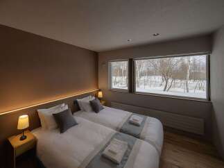 Experience cozy winter nights in this inviting hotel room, featuring two comfortable twin beds adorned with crisp white linens and plush pillows.
