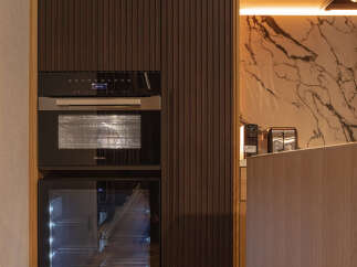 Experience modern luxury with this sleek kitchen featuring dark wood cabinetry and integrated Miele appliances.