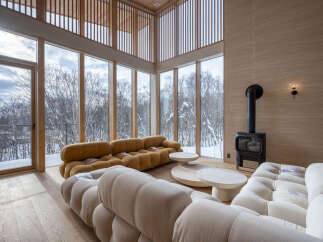 Experience breathtaking winter views from this stunning living room, featuring floor-to-ceiling windows that showcase a snow-covered forest landscape.