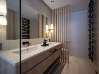 Experience modern luxury in this stunning bathroom featuring a sleek double vanity with stone countertops and elegant wooden cabinetry.