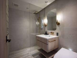 Experience modern luxury in this stunning bathroom, featuring a sleek vanity with ample storage and a striking gold shower fixture.