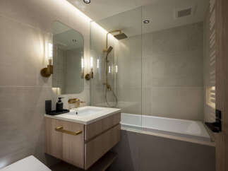 Experience modern luxury in this stunning bathroom, featuring a sleek vanity with gold accents and a spacious bathtub.