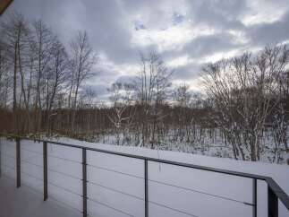Experience serene winter living with this stunning property, offering a picturesque view of snow-covered trees and a tranquil landscape.