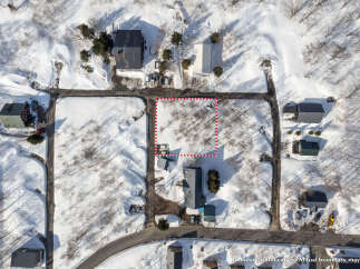 Explore this picturesque winter scene featuring a vacant lot outlined by a dotted red boundary, perfect for your dream home.