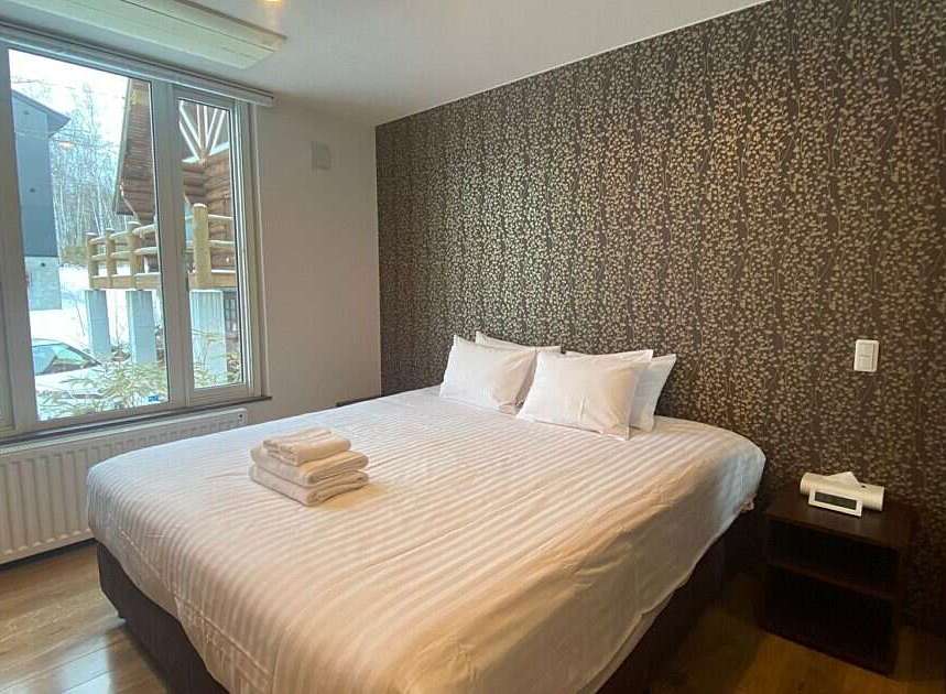 Experience comfort and style in this beautifully appointed bedroom, featuring a plush king-sized bed with crisp white linens and a striking patterned wallpaper accent wall.