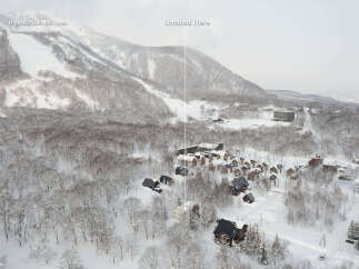 Discover your dream mountain getaway with this stunning aerial view of a ski resort village nestled amidst snow-covered trees.