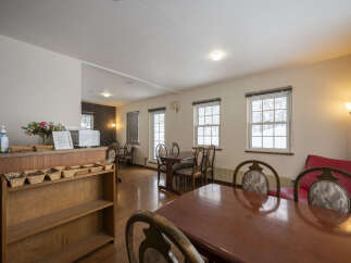This inviting space features a communal dining area with multiple tables and chairs, perfect for gatherings.