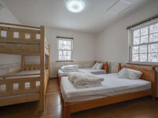 This charming bedroom features a space-saving bunk bed and two comfortable single beds, perfect for accommodating families or groups.