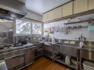 This spacious kitchen features a large stainless steel gas range and double sinks, perfect for preparing meals.