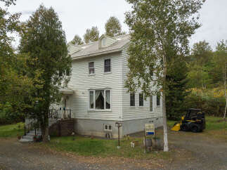 Discover this charming white clapboard house nestled amidst lush greenery and mature trees.