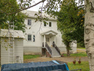 Discover this charming white clapboard house nestled amongst mature trees, offering a serene and private setting.