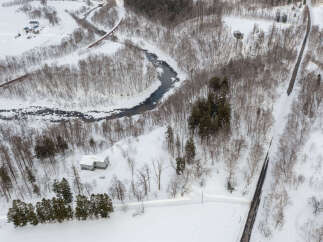 Discover a serene winter wonderland with this aerial view of a secluded property nestled amongst snow-covered trees.