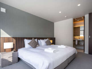 Experience comfort and style in this beautifully appointed bedroom, featuring a plush king-sized bed adorned with crisp white linens and accent pillows.