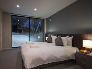 Experience ultimate comfort in this luxurious bedroom, featuring a king-sized bed with crisp white linens and plush pillows.
