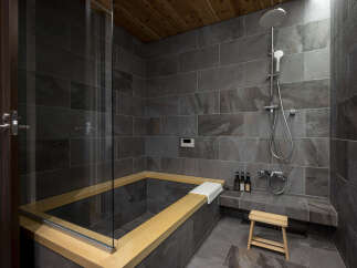 Experience ultimate relaxation in this luxurious bathroom featuring a deep soaking tub with a wooden surround and a separate rainfall shower.