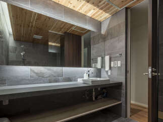 Experience modern luxury in this stunning bathroom featuring a sleek concrete vanity and a spacious walk-in shower with elegant stone tilework.