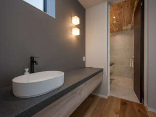 Experience modern luxury in this bathroom featuring a sleek vessel sink atop a dark countertop and a floating wood vanity.