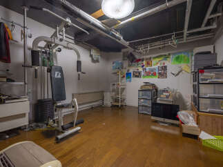 This versatile room offers a dedicated home gym space with a weight machine and ample storage solutions, including shelving units and drawers.
