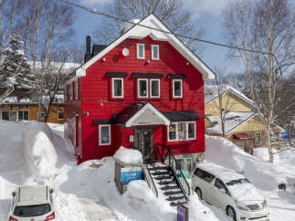 Discover this charming red house nestled in a snowy landscape, perfect for a winter getaway.