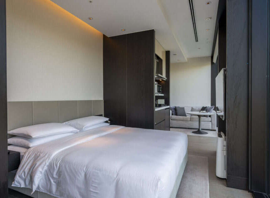 Experience luxurious comfort in this modern hotel room, featuring a plush king-sized bed with crisp white linens and a stylish upholstered headboard.