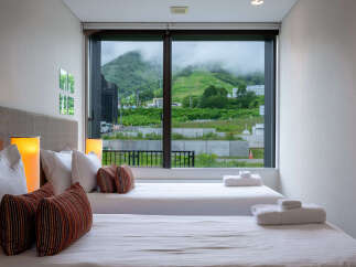 Experience breathtaking mountain views from this serene bedroom, featuring two comfortable twin beds perfect for relaxation.