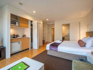 This modern studio apartment features a compact kitchenette equipped with a microwave and refrigerator, perfect for preparing simple meals.