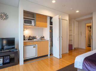 Discover modern living in this compact studio apartment, featuring a well-equipped kitchenette with a microwave and mini-fridge.