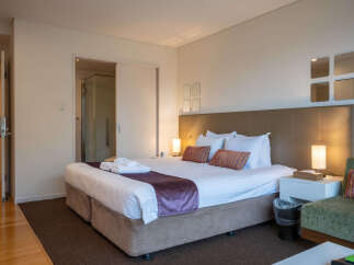 Experience comfort and style in this well-appointed hotel room, featuring a plush king-sized bed adorned with crisp white linens and decorative pillows.
