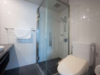 Experience modern comfort in this well-appointed bathroom, featuring a sleek glass-enclosed shower with a rainfall showerhead and a convenient bidet toilet.