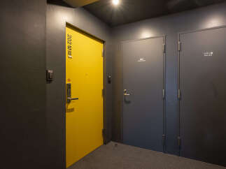 Discover modern living with this image showcasing a bright yellow apartment door and two adjacent grey doors, one labeled 'owner's storage' and the other 'linen store'.