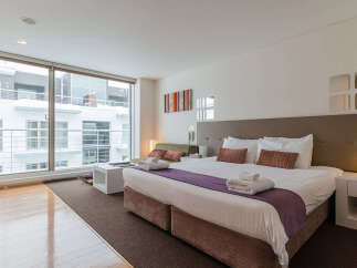 Experience modern comfort in this stylish studio apartment, featuring a plush king-sized bed and a cozy seating area.