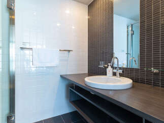 This modern bathroom features a sleek vanity with a white basin sink and a chrome faucet, complemented by a dark wood countertop.