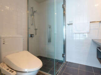 Experience modern comfort in this well-appointed bathroom, featuring a sleek toilet with a bidet function and a spacious glass-enclosed shower.