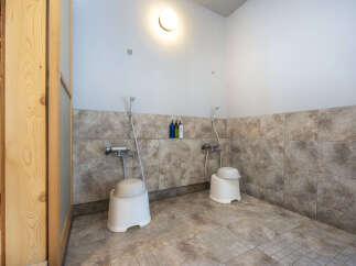 Experience a refreshing cleanse in this modern shower area, featuring two individual shower stalls equipped with handheld showerheads and comfortable seating.