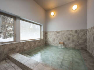 Experience ultimate relaxation in this serene indoor hot spring, featuring a spacious soaking tub with a gentle waterfall feature.