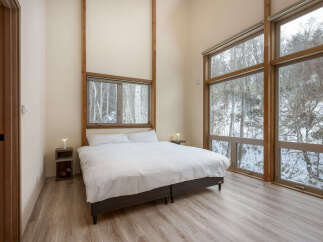 Experience serene living in this modern bedroom, featuring a comfortable queen-sized bed dressed in crisp white linens.