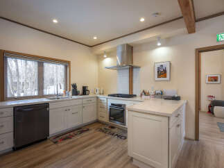 Discover this charming kitchen featuring a sleek stainless steel range hood and a modern gas stovetop, perfect for culinary enthusiasts.
