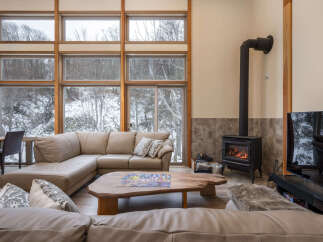 Experience cozy living in this spacious living room featuring a large sectional sofa and a rustic wood coffee table adorned with a puzzle.