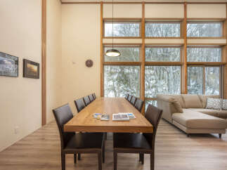 Experience breathtaking winter views from this spacious dining area, featuring a large wooden table perfect for gatherings.