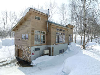 Experience the charm of this wooden house nestled in a serene, snow-covered landscape.