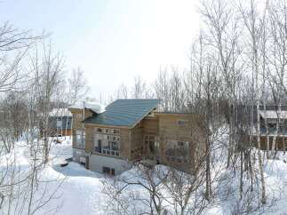 Experience serene winter living in this modern wooden home nestled amidst snow-covered trees.