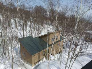 Experience the charm of this wooden cabin nestled amidst a serene winter forest.