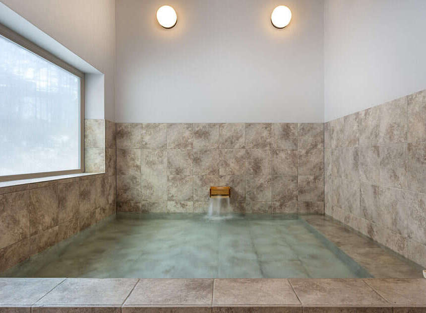 Experience ultimate relaxation in this serene bathroom featuring a spacious soaking tub with a gentle waterfall feature.