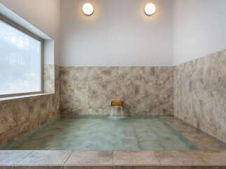 Experience ultimate relaxation in this serene bathroom featuring a spacious soaking tub with a gentle waterfall feature.