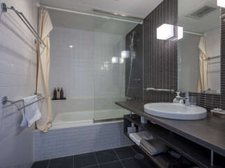 Experience modern comfort in this well-appointed bathroom, featuring a sleek bathtub with a glass enclosure and a spacious vanity with ample storage.