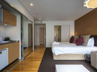 Discover modern comfort in this studio apartment, featuring a well-equipped kitchenette with ample cabinet space and a compact refrigerator.