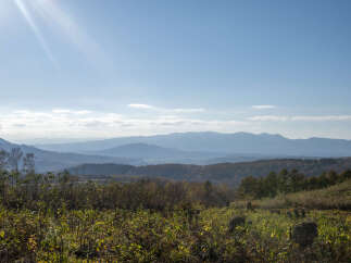 Discover breathtaking panoramic views from this stunning property, showcasing rolling hills and distant mountains under a clear blue sky.