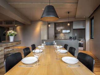 Experience elegant dining in this modern home, featuring a spacious wooden table set for eight with fine glassware and cutlery.